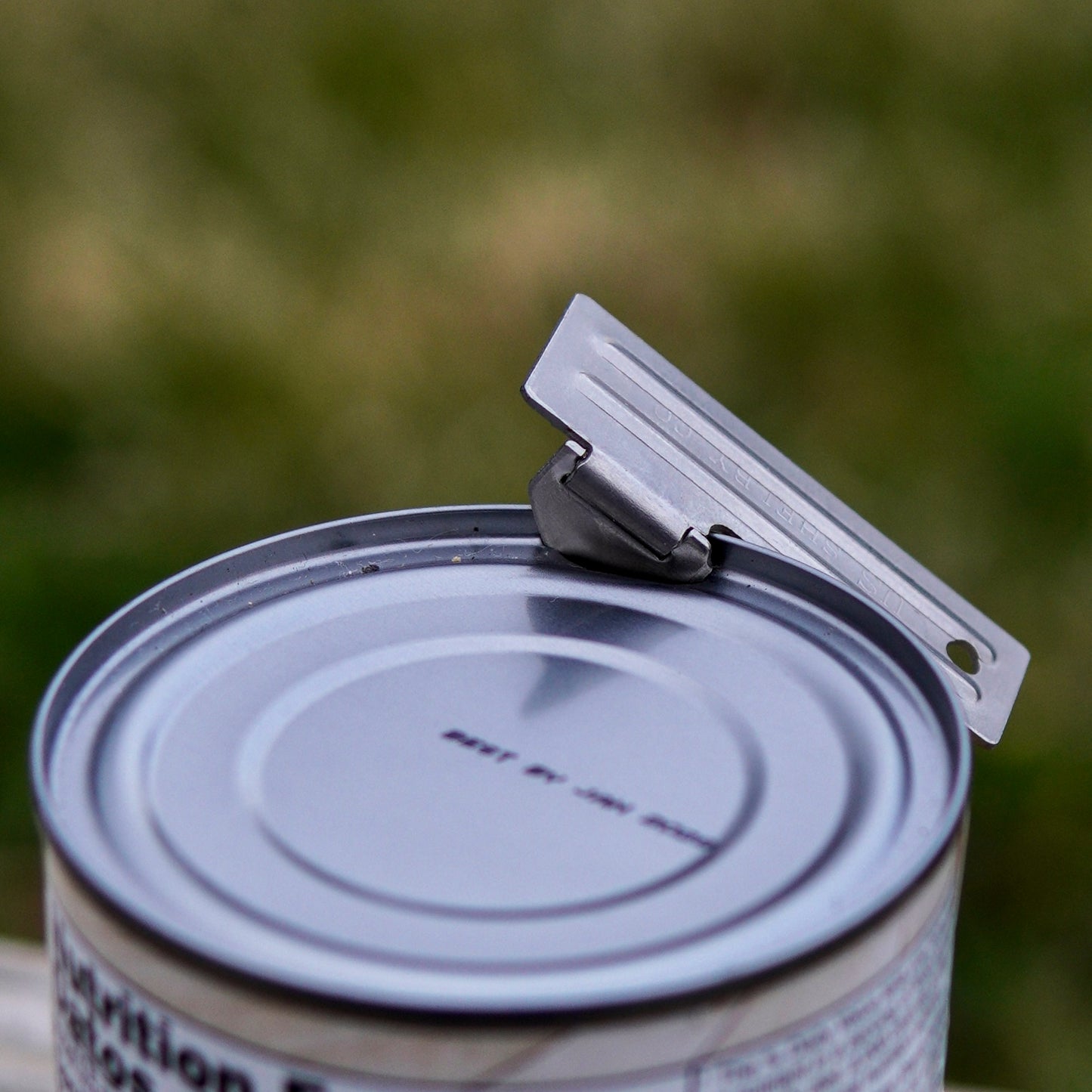 Can opener on a can with a blurred green background