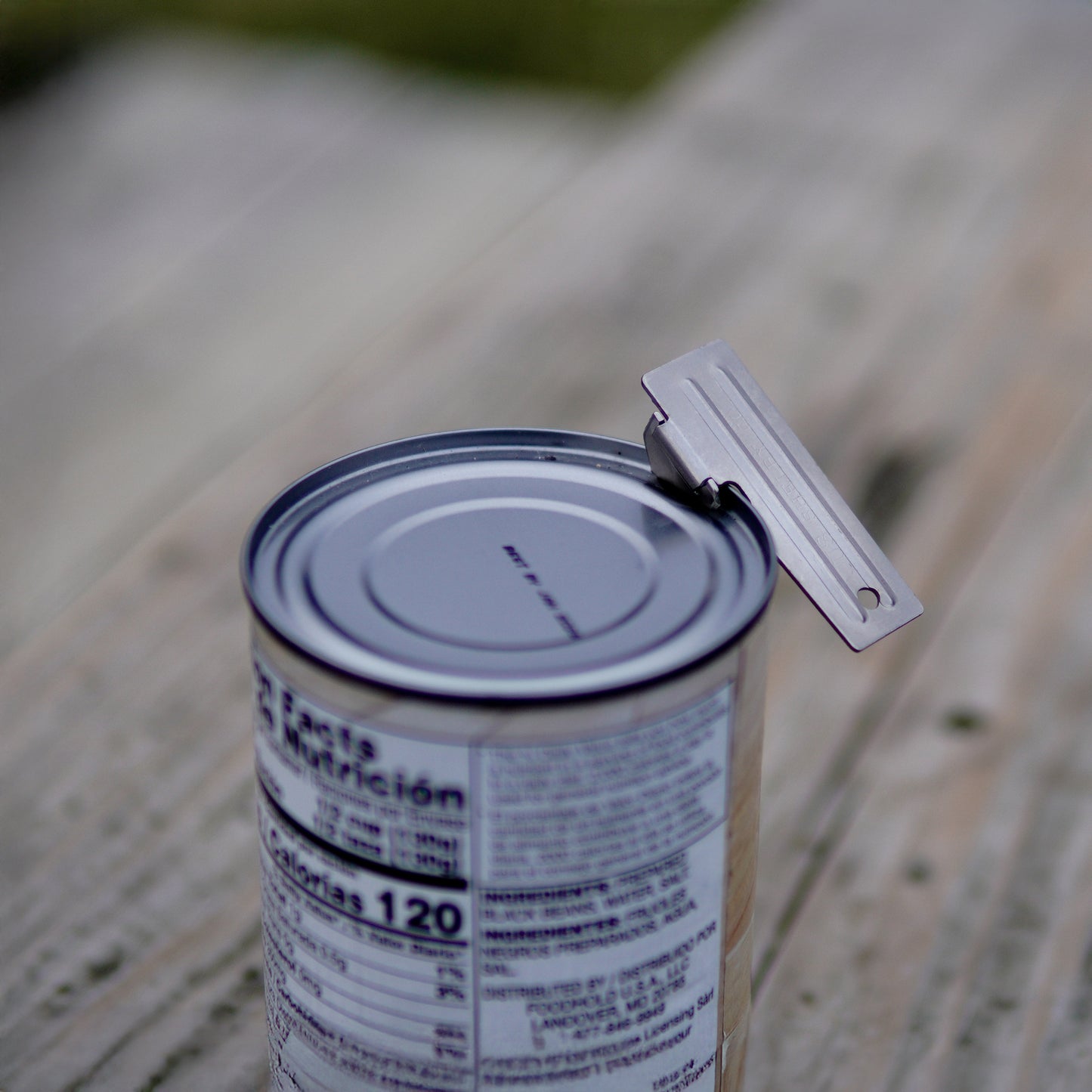 Can opener on a can with blurred natural background